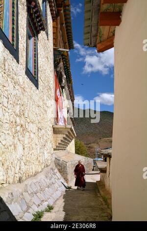 Monastère de Sumtseling au-dessus de la ville de Shangri la, Yunnan. Style tibétain, bâtiments au sommet d'or. Un moine marche à travers les ruelles étroites Banque D'Images