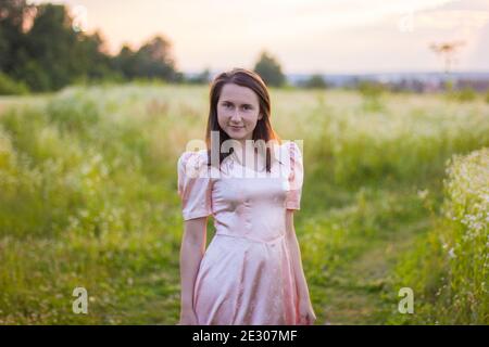 fille debout dans le champ dans une robe rose Banque D'Images