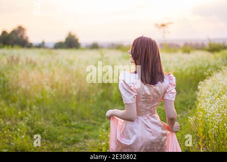 fille debout dans le champ dans une robe rose Banque D'Images