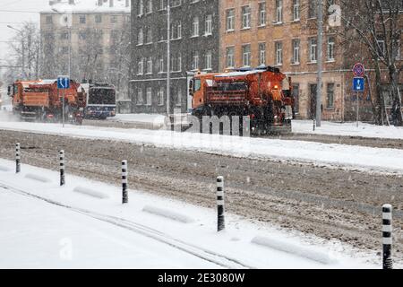 RIGA, LETTONIE 2021 janvier 11 : le nettoyeur de la neige nettoie les routes enneigées et élimine le sel. Tempête de neige et circulation dense Banque D'Images