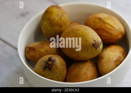 Un bol de baies mûres de Chiku ou de Sepadilla. Manilkara zapota est également connu sous le nom de sapodilla, sapota, chikoo, naseberry, ou nispero. Banque D'Images