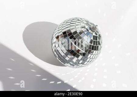 Boule disco brillante sur fond blanc avec des ombres dures. Boule disco aux rayons lumineux - image Banque D'Images