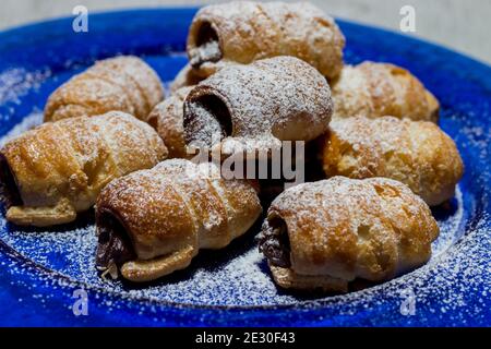 Cannoli au chocolat. Bonbons au chocolat italien sur une assiette bleue et un fond blanc. Banque D'Images