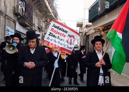 Les membres de Neturei Karta, un mouvement juif ultra-orthodoxe en marge au sein du bloc antisioniste, portent le drapeau palestinien et crient des slogans lorsqu'ils traversent le quartier religieux de MEA Shearim le 14 janvier 2021, à Jérusalem, en Israël. Neturei Karta s'oppose au sionisme et appelle à un « démantèlement pacifique » de l'État d'Israël, dans la croyance que les Juifs sont interdits d'avoir leur propre état jusqu'à la venue du Messie juif et que l'état d'Israël est une rébellion contre Dieu. Banque D'Images