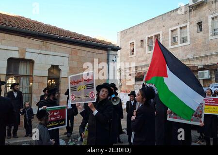 Les membres de Neturei Karta, un mouvement juif ultra-orthodoxe en marge au sein du bloc antisioniste, portent le drapeau palestinien et crient des slogans lorsqu'ils traversent le quartier religieux de MEA Shearim le 14 janvier 2021, à Jérusalem, en Israël. Neturei Karta s'oppose au sionisme et appelle à un « démantèlement pacifique » de l'État d'Israël, dans la croyance que les Juifs sont interdits d'avoir leur propre état jusqu'à la venue du Messie juif et que l'état d'Israël est une rébellion contre Dieu. Banque D'Images