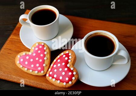 Deux tasses de café et biscuits glaçtants royaux en forme de cœur à pois avec une attention sélective Banque D'Images
