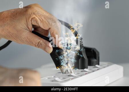Main âgée avec étincelle de prise électrique Banque D'Images