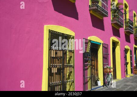 Façade d'une boutique de souvenirs de style colonial avec un mur en stuc rose, des fenêtres aux finitions jaunes et des grilles en fer artisanales à Puebla de Zaragoza, au Mexique. Banque D'Images