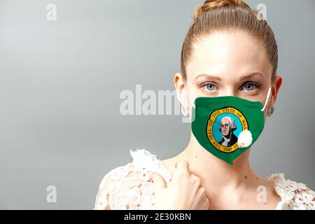 Portrait d'une jeune femme portant un masque de protection du visage avec le drapeau de l'État américain de Washington pour prévenir le coronavirus. Banque D'Images