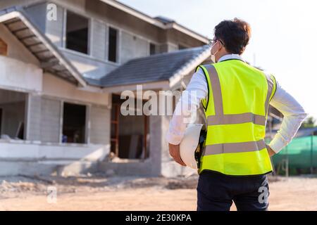 Architecte regardant quelques détails et tenir un casque sur une construction, concept de constructeur de maison. Banque D'Images