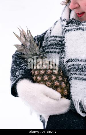 Une fille en moufles tient l'ananas en hiver Banque D'Images