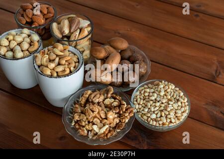 Mélanger les noix dans un bol sur une table en bois. Noix, noix de pécan, amandes, noisettes, macadamia, noix de cajou et pignons Banque D'Images
