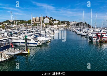 Perspective vue sur les bateaux amarrés le long des pontons dans le port intérieur de Torquay avec ciel bleu et bâtiments éloignés. Un arrêt populaire pour les visiteurs de Torbay. Banque D'Images