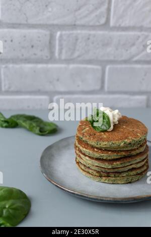 Crêpes aux épinards et aux bananes avec feuilles fraîches sur une assiette grise sur fond gris. Concept d'alimentation saine. Orientation verticale. Copier l'espace. Banque D'Images