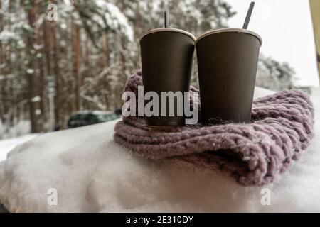 Deux tasses en papier avec café gardent au chaud sur un foulard dans la neige, conte d'amour d'hiver Banque D'Images