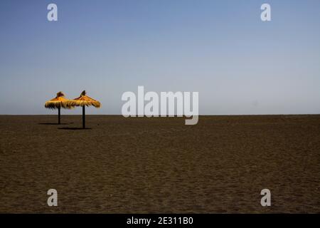 Vue panoramique sur une plage déserte vide avec deux chaume isolés parasols en paille - industrie touristique pronostic concept Banque D'Images