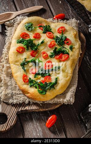 Délicieux focaccia avec des jeunes épinards, de l'ail et des tomates cerises Banque D'Images