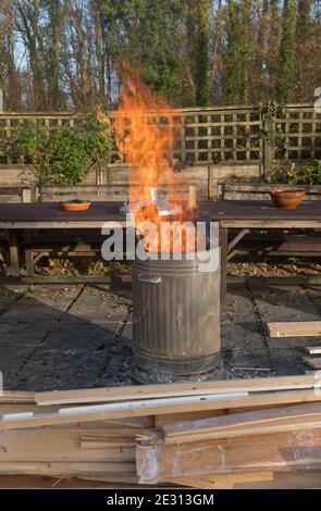 Combustion de bois dans un incinérateur en acier galvanisé dans un jardin à Rural Devon, Angleterre, Royaume-Uni Banque D'Images