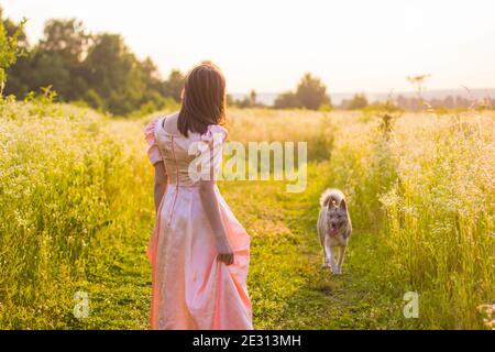 fille debout dans le champ dans une robe rose Banque D'Images