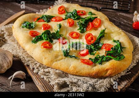 Délicieux focaccia avec des jeunes épinards, de l'ail et des tomates cerises Banque D'Images