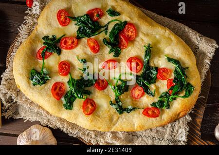 Délicieux focaccia avec des jeunes épinards, de l'ail et des tomates cerises Banque D'Images