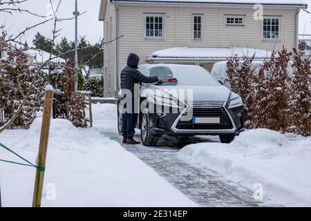 Vue de l'homme qui nettoie le pare-brise de la neige. Contexte du concept de véhicule. Suède. Uppsala. Banque D'Images