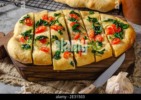 Délicieux focaccia avec des jeunes épinards, de l'ail et des tomates cerises Banque D'Images