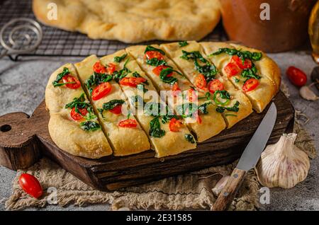 Délicieux focaccia avec des jeunes épinards, de l'ail et des tomates cerises Banque D'Images