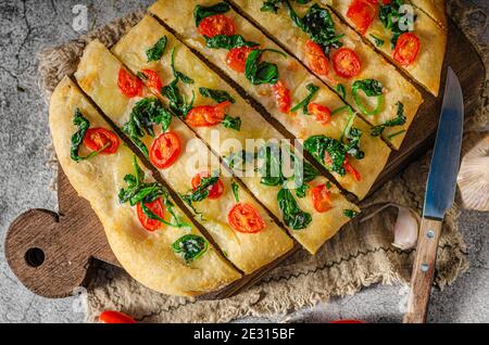 Délicieux focaccia avec des jeunes épinards, de l'ail et des tomates cerises Banque D'Images