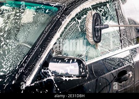 Gros plan de la brosse de nettoyage sur la voiture au lavage de voiture Banque D'Images