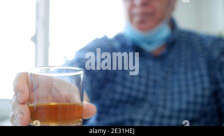 Image avec un homme qui boit de l'alcool en portant un masque de protection Sur son visage Banque D'Images