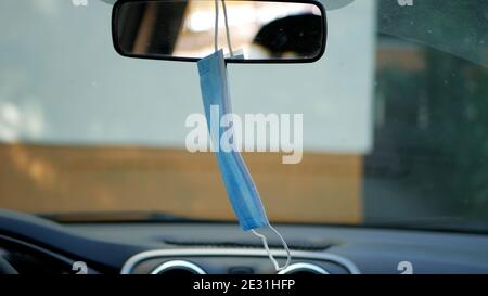 Masque médical utilisé par le conducteur suspendu sur le Rétroviseur intérieur de la voiture Banque D'Images