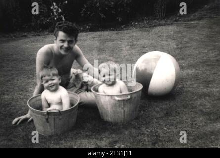 Jumeaux identiques dans des bains d'étain avec leur père dans Lancashire, Royaume-Uni dans les années 1950 Banque D'Images