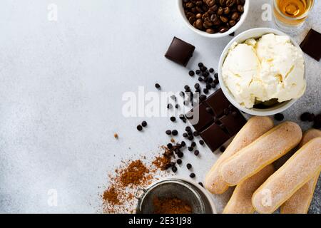 Ingrédients pour préparer un dessert italien tiramisu, savoiardi, mascarpone, poudre de cacao et chocolat sur fond de béton léger. Vue de dessus avec copie Banque D'Images