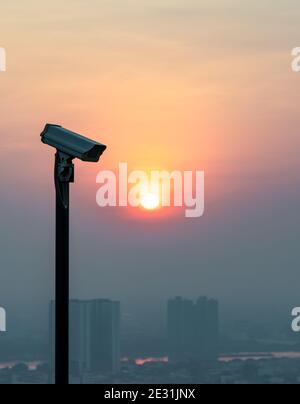 Caméra de surveillance moderne sur fond urbain et gratte-ciel avec soleil criant vif avant le coucher du soleil. Le concept de surveillance evenin Banque D'Images