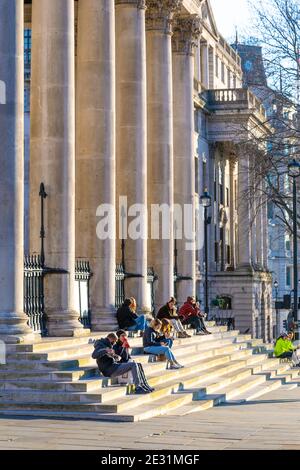 9 janvier 2021 Londres, Royaume-Uni - les personnes assises sur les marches de St Martin-in-the-Fields à Trafalgar Square pendant une épidémie ensoleillée de coronavirus nous enferme Banque D'Images