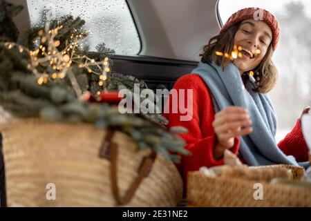 Femme souriant et regardant le sparkler en étant assise en voiture coffre Banque D'Images