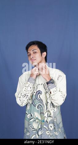 homme asiatique élégant avec des vêtements batik en studio isolé avec arrière-plan bleu Banque D'Images