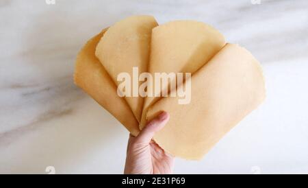 Main tenant de nombreux morceaux de kuih kapit, un en-cas de galette d'oeufs populaire en Indonésie, Malaisie, Brunei et Singapour. Banque D'Images