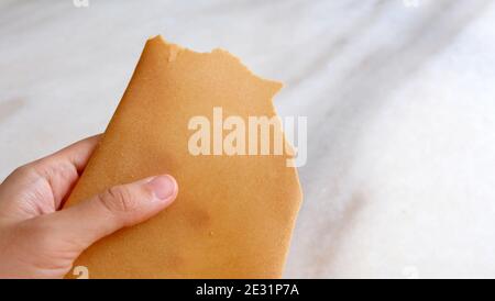 Main tenant une variante de kuih kapit, un en-cas de galette d'oeufs populaire en Indonésie, Malaisie, Brunei et Singapour. Banque D'Images