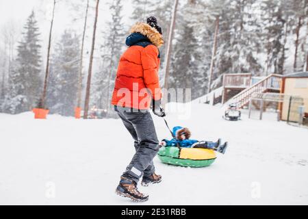 Les garçons jouent sur un toboggan en hiver - promenade un tubing gonflable - vacances d'hiver Banque D'Images
