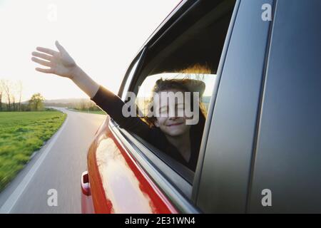 La fille dans la voiture a coincé sa main dans le vent. Déplacement. Banque D'Images