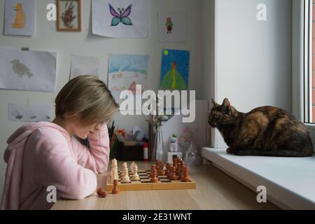Une fille joue à un jeu de société en gros plan. Échecs. Banque D'Images