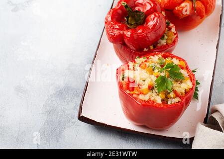 Poivrons rouges farcis avec du riz et des légumes sur un bol en céramique sur fond de bétons gris. Vue de dessus. Banque D'Images