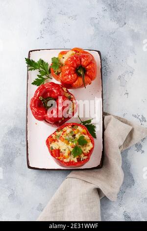 Poivrons rouges farcis avec du riz et des légumes sur un bol en céramique sur fond de bétons gris. Vue de dessus. Banque D'Images