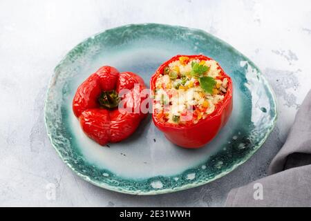 Poivrons rouges farcis avec du riz et des légumes sur un bol en céramique sur fond de bétons gris. Vue de dessus. Banque D'Images