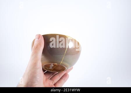 Bol japonais Kintsugi brun restauré avec de l'or Banque D'Images