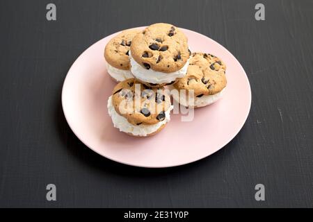 Sandwich maison à la crème glacée au chocolat sur une assiette rose sur fond noir, vue latérale. Banque D'Images