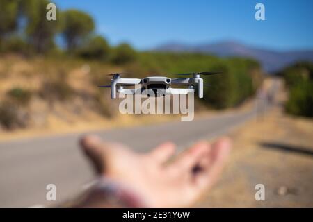 main saisissant un drone volant à l'extérieur à côté d'une route avec des arbres en arrière-plan Banque D'Images