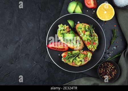 Trois toasts avec guacamole et romarin sur fond noir. Banque D'Images